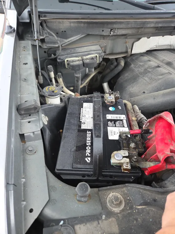 New battery fitted in an engine bay with the terminals being connected during an on-site replacement
